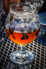 glass of craft beer on outdoor patio table in sunlight
