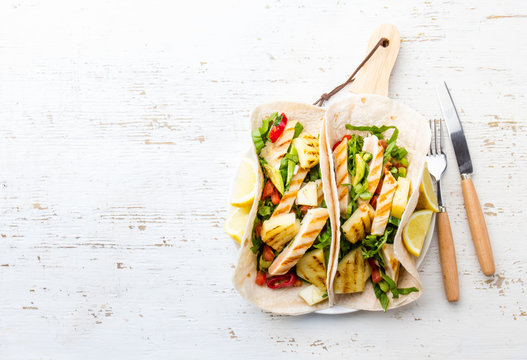 Mexican tacos with grilled chicken and pineapple on wooden background with cutlery. Copy space
