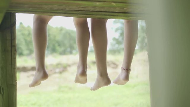 Brother and sister sitting side by side with feet dangling