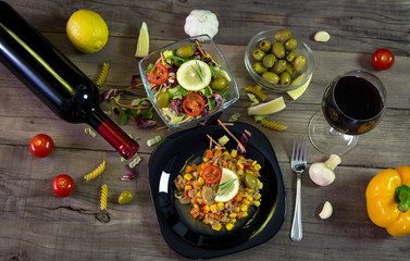 Milanez salat with fresh vegetable, olives, lemon, tomato, papper, garlik, mushrooms and wine in background. Mediterian food