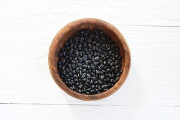 black beans in wooden bowl isolated on white background