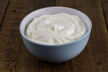Bowl of natural Greek yoghurt isolated on wooden rustic background