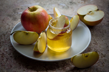 Organic honey in glass jar and red apple on the plate
