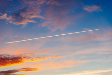 Trace of aircraft in the dramatic sky on sunset