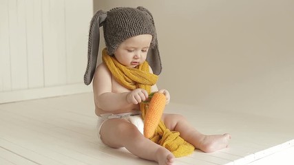 Portrait of a baby in a bunny suit. Little boy laughs and plays with toy