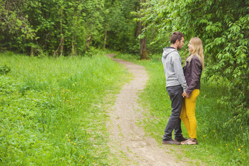 Fototapeta premium Young man and woman happy walking along the trail in the park in spring evening.