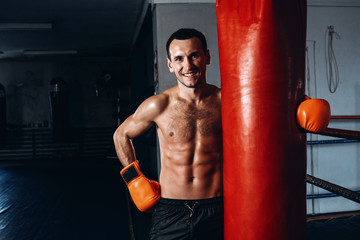 Male boxer training in dark gym. Strong Athletic Man Fitness Model Torso showing six pack abs.