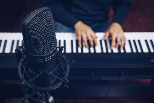 condenser microphone on male musician hands playing piano background