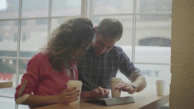Friends using digital tablet together in coffee shop