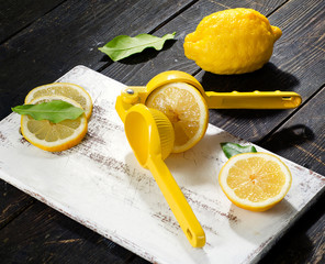 Squeezer and lemons on a dark wooden board