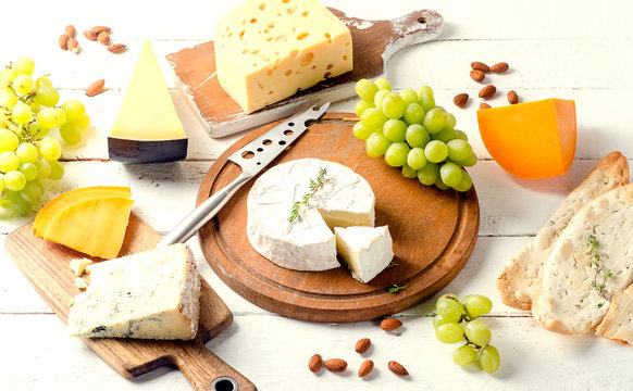 Different kinds of cheeses on  white wooden board