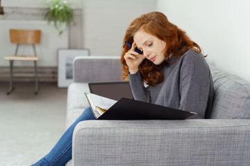 frau sitzt auf dem sofa und schaut mit ernstem gesicht auf ihre unterlagen