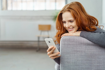 frau liegt auf dem sofa und liest eine nachricht