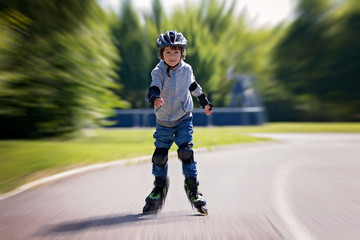 Cute little child, boy, riding on a rollerblades in the park