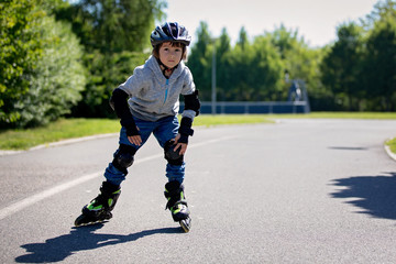 Cute little child, boy, riding on a rollerblades in the park