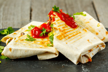 Vegetarian burritos wraps with beans, avocado and cheese on a slate. Love for a healthy vegan food concept