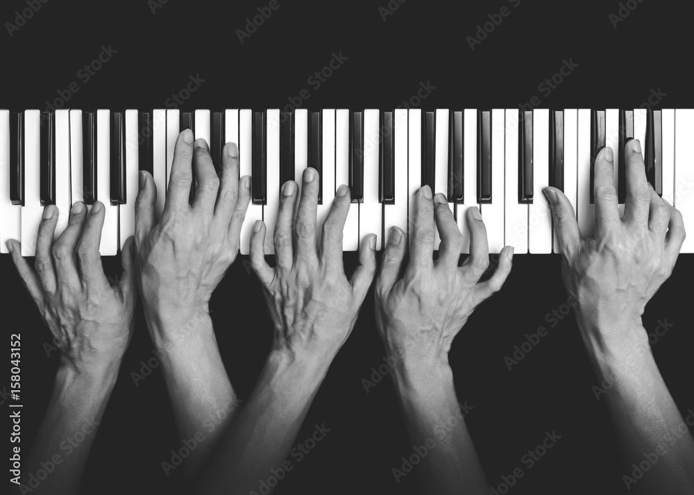 Wall mural five hands playing on piano keys, black and white. music background