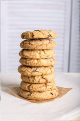 Chocolate biscuits and a glass of milk on a linen towel on a wooden table with a white background. Vintage view. Place for the inscription.