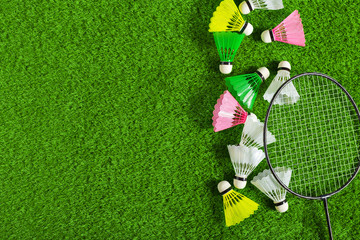 Shuttlecock and badminton racket on green grass