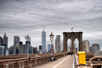 Brooklyn Bridge  walkway in New York City with pedestrians in the distance on an overcast day