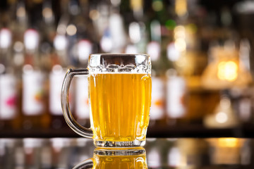 Closeup image of mug with golden cold light beer at bar background.