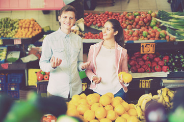 Young girl and smiling boyfriend buying citruses