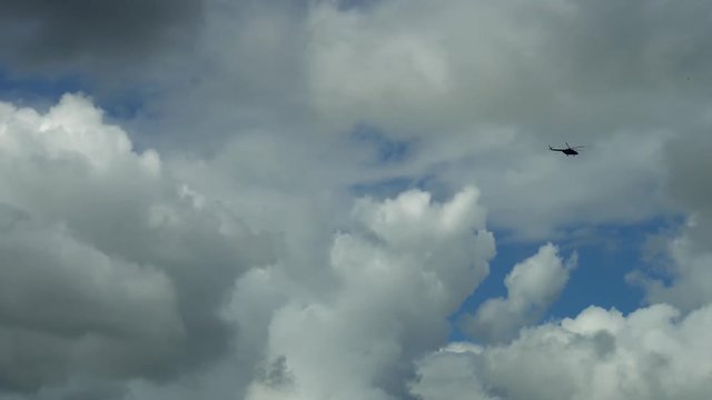 helicopter flying high in the sky in the far distance.