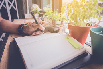 man hand write a short note on opened notebook with pen. Flat layout and copy space.