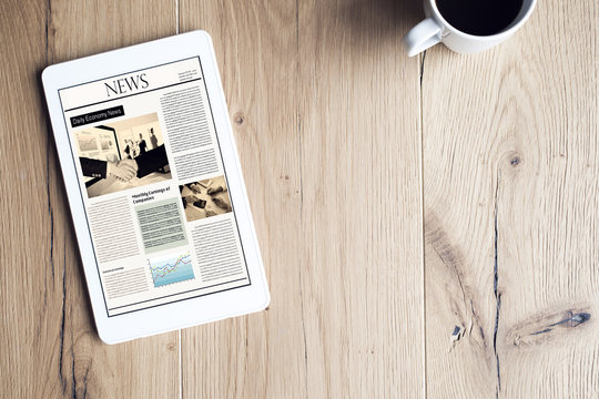 Newspaper On Digital Tablet On Wooden Table