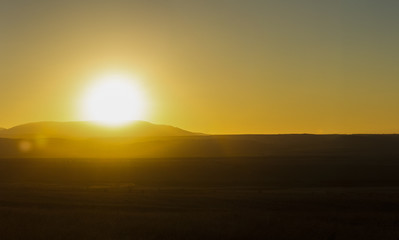 The sun sets over the hill above the valley