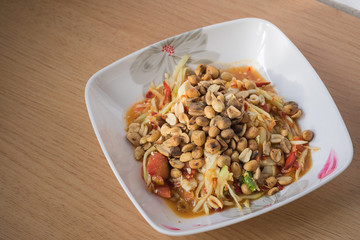 Papaya salad in the dish on the wood floor.