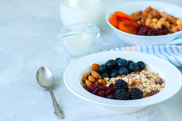 Healthy breakfast concept. Homemade granola with blackberry, dry cranberry, blueberry, almond, yogurt in a jar, sour cream and milk on a wooden background. Close up and copy space.