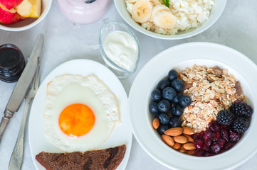 Healthy breakfast concept. Homemade granola with blackberry, dry cranberry, blueberry, almond, yogurt in a jar, sour cream and milk on a wooden background. Close up and copy space.