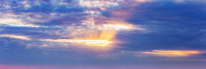 background, panorama of the sky, the sun's rays make their way through the dark dramatic clouds
