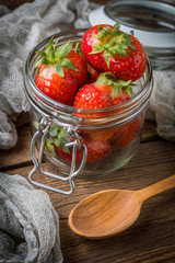 Strawberry in jar on wooden background.