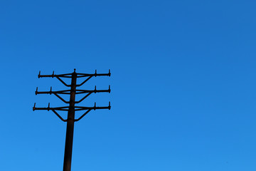 Old metal power tower without wires against clear blue sky
