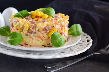 Salad with smoked sausage, corn, cheese, fresh carrot, egg, garlic and yogurt on a white plate on a abstract background