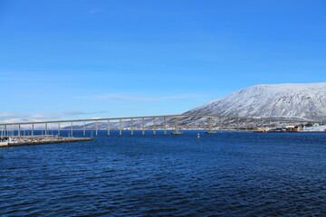 Obraz premium beautiful panoramic view from boat on Tromso landscape with snowy mountains and city harbor in sunny blue sky, Norway