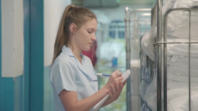 Woman taking inventory of towels in hotel laundry room