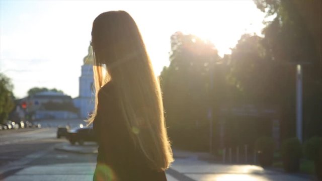 Happy girl with long hair having fun outdoor in the city at sunrise. Beauty woman spinning, jumping and laughing. Freedom. Slow motion video footage.