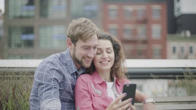Couple sitting together in park looking at smart phone
