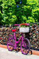 Fototapeta na wymiar pink bike standing on the bridge of love