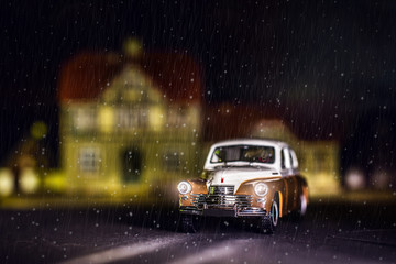 Photo of a miniature car GAZ-M20. Retro car rides through the city on a winter night. Snowing....
