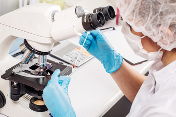 Professional scientist doing research with microscope in clinical laboratory. .
