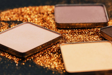 Pressed eyeshadows lie on golden glitter
