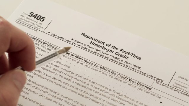 An anonymous person reads the IRS form 5405 which is used for the repayment of a previously claimed first time homebuyer tax credit.
