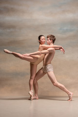 Couple of ballet dancers posing over gray background