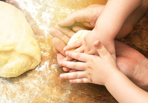 Hands of father and baby son together kneading the dough