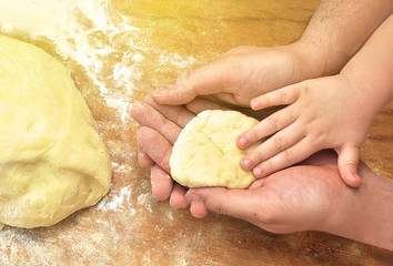 Hands of father and baby son together kneading the dough