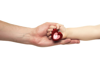 hand of the father holding the hand of a small child with a red heart
